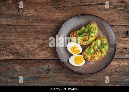 Antipasto vegetariano con sandwich di avocado e uova sode a fette su sfondo di legno. Foto Stock
