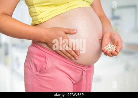 Donna incinta con pillole in mano - medicina durante la gravidanza Foto Stock