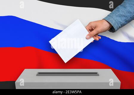 Elezioni in Russia - votazione alle urne. La mano dell'uomo sta mettendo il suo voto nelle urne. Illustrazione con rendering 3D. Foto Stock