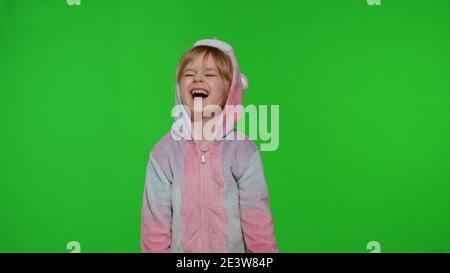 Bambino piccolo biondo giovane 5-6 anni in costume unicorno piangendo con le lacrime su sfondo chiave chroma. Ritratto di animatore ragazzino in pigiami unicorno. Spazio di copia Foto Stock