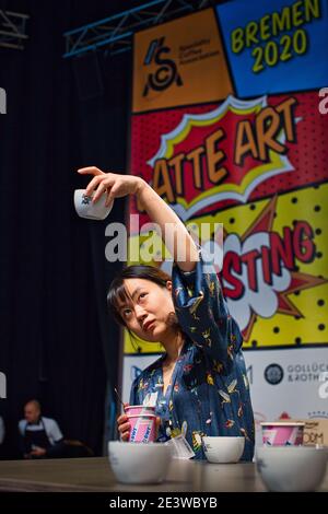 Femmina che tiene in aria una tazza di caffè al campionato tedesco di degustazione di Coppa, 2020 a Brema, Germania Foto Stock
