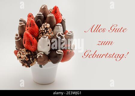 Felice biglietto d'auguri di compleanno in lingua tedesca con scritta rossa che recita Alles Gute zum Geburtstag; UN mazzo di fiori commestibili, disposizione di cho Foto Stock