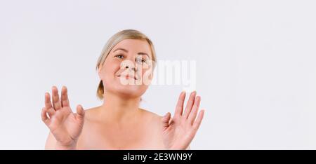 Banner - formato lungo. Una donna anziana con un sorriso pone e mostra mani sane e idratate, morbide alla telecamera su sfondo bianco con spazio per Foto Stock