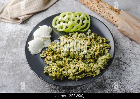 Uova strapazzate biologiche con spinaci in piastra su tavolo di marmo e pane Foto Stock