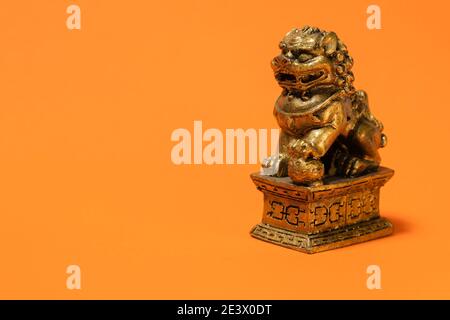 Leone scultura della cultura cinese. Molto popolare cinese ornamento decorativo e religioso. Sfondo arancione. Foto Stock