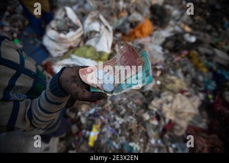 Neu Delhi, India. 18 gennaio 2021. Il decennale Shekh Zahid mostra i soldi che ha guadagnato dopo aver venduto gli articoli riciclabili mentre raccoglieva la spazzatura alla discarica di spazzatura di Bhalswa. Il quarto classificato di Malda nel Bengala Occidentale, il cui padre lavora come pilota di risciò, ha iniziato a lavorare durante la chiusura delle scuole nell'ottobre 2020. La sua famiglia lo mandò a Delhi per stare con uno zio che già lavorava come picchiatore di straccio. Shek guadagna 150 rupie, circa 1.70 euro al giorno, raccogliendo materiale riciclabile dalla spazzatura. Credit: Vijay Pandey/dpa/Alamy Live News Foto Stock