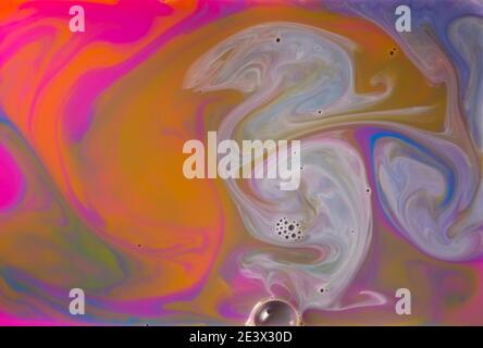 I liquidi colorati si mescolano insieme in un fluido creando uno sfondo astratto colorato Foto Stock