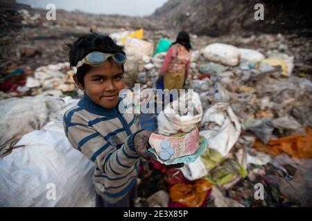 18 gennaio 2021, India, Neu Delhi: Il decennale Shekh Zahid mostra i soldi che ha guadagnato dopo aver venduto gli articoli riciclabili mentre raccogliendo i rifiuti alla discarica di spazzatura di Bhalswa. Il quarto classificato di Malda nel Bengala Occidentale, il cui padre lavora come pilota di risciò, ha iniziato a lavorare durante la chiusura delle scuole nell'ottobre 2020. La sua famiglia lo mandò a Delhi per stare con uno zio che già lavorava come picchiatore di straccio. Shek guadagna 150 rupie, circa 1.70 euro al giorno, raccogliendo materiale riciclabile presso la discarica dei rifiuti. (Al dpa 'domo del mondo: La povertà spinge milioni di bambini a. Foto Stock