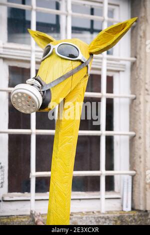 Scultura gialla con maschera a gas davanti A A. Finestra Foto Stock