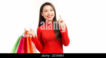 Donna asiatica felice che indossa un abito di ao dai tradizionale con borse shopping godendo in shopping nel giorno nuovo lunare. Foto Stock