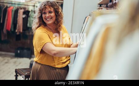 Donna sorridente che lavora in un negozio di moda. Venditore che lavora in una boutique. Foto Stock