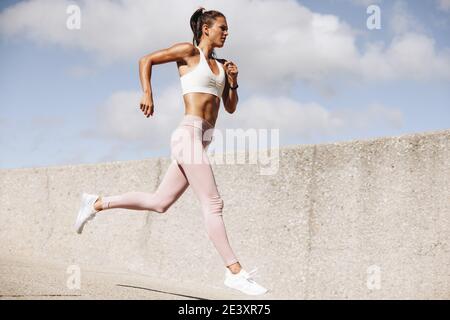 Donna sportiva che corre all'aperto al mattino. Atleta femminile in abbigliamento da corsa che si esercita la mattina. Foto Stock