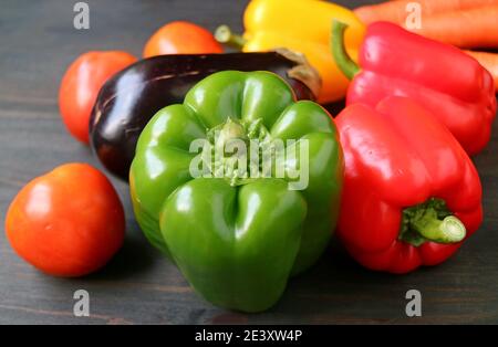 Primo piano di un peperone verde con altre verdure colorate su sfondo di legno Foto Stock