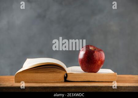 sul tavolo di legno, un libro aperto con una mela rossa su di esso. copia spazio Foto Stock