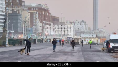 Brighton UK 21 gennaio 2021 - camminatori al mattino presto sul lungomare di Brighton e Hove durante un mix di sole e docce pesanti come la coda di Storm Christoph lascia la Gran Bretagna dopo aver causato inondazioni nelle parti settentrionali dell'Inghilterra e del Galles: Credit Simon Dack / Alamy Live News Foto Stock