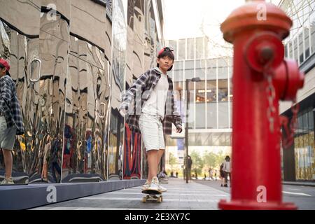 teenage asiatico bambini skateboard all'aperto in strada Foto Stock