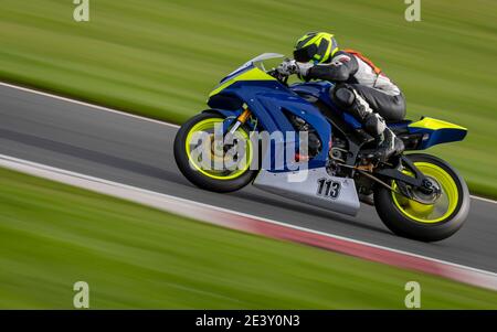 Un'inquadratura panoramica di una moto da corsa che si curva su una pista. Foto Stock