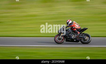 Un'inquadratura panoramica di una moto da corsa che si curva su una pista. Foto Stock