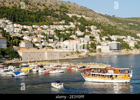 Croazia: Dubrovnik. Imbarcazione passeggeri che ritorna dall'isola di Lokrum e barche ormeggiate al pontile nel porticciolo, nella città vecchia, vista dalla rampa Foto Stock