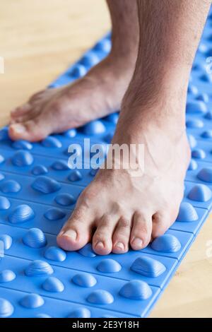 uomo facendo flatfoot correzione ginnastica esercizi a piedi sul tappetino massaggio a casa Foto Stock