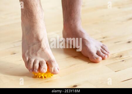 uomo che fa la ginnastica di correzione del piede piatto usando la sfera di massaggio nel paese Foto Stock