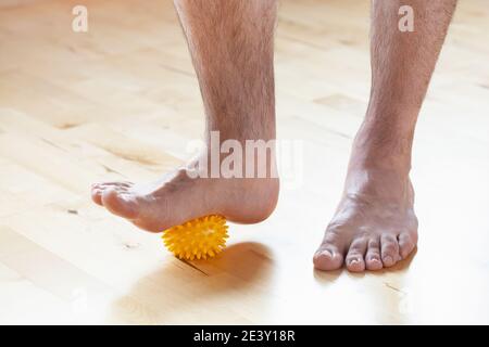 uomo che fa la ginnastica di correzione del piede piatto usando la sfera di massaggio nel paese Foto Stock