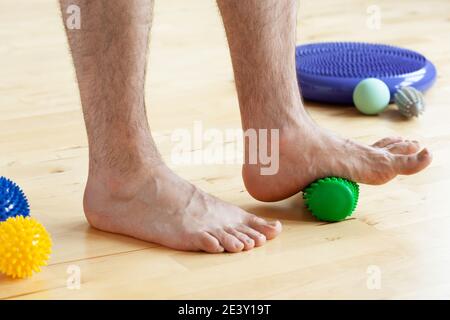 uomo che fa la ginnastica di correzione del piede piatto usando il rullo di massaggio nel paese Foto Stock