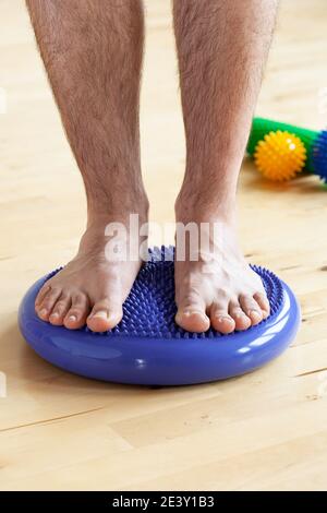 l'uomo che fa la correzione piatta dell'esercitazione che si esercita l'equilibratura sul cuscino di massaggio nel paese Foto Stock