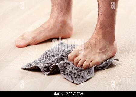 uomo facendo flatfoot correzione ginnastica esercizi afferrare asciugamano a casa Foto Stock