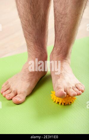 uomo che fa la ginnastica di correzione del piede piatto usando la sfera di massaggio nel paese Foto Stock