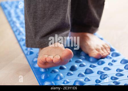 uomo facendo flatfoot correzione ginnastica esercizi a piedi sul tappetino massaggio a casa Foto Stock