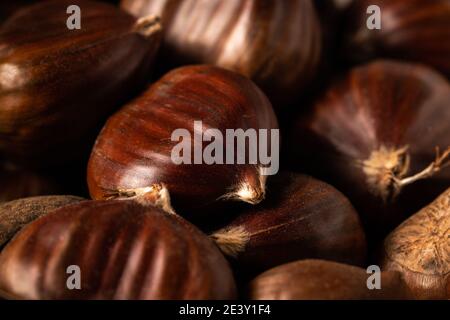 Un mucchio di castagne dolci appena raccolte su sfondo scuro. angolo di visualizzazione di 45 gradi, macro shot full frame. Foto Stock