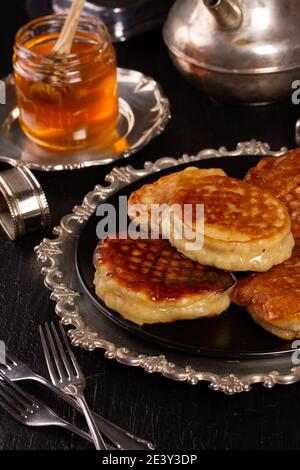 Le deliziose frittelle fresche si trovano in un piatto di metallo che si erge sul tavolo da cucina Foto Stock