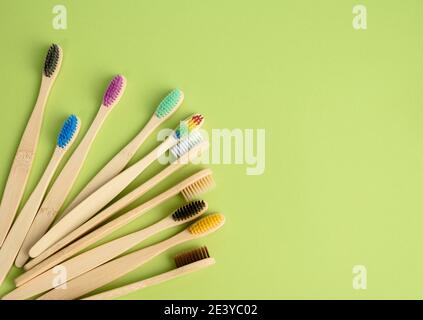 spazzolini da denti in legno multicolore su sfondo verde, concetto di rifiuto in plastica, zero rifiuti, vista dall'alto Foto Stock