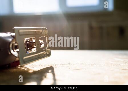 il processo di segatura del legno compensato con un seghetto elettrico, un uomo tiene in mano un utensile Foto Stock