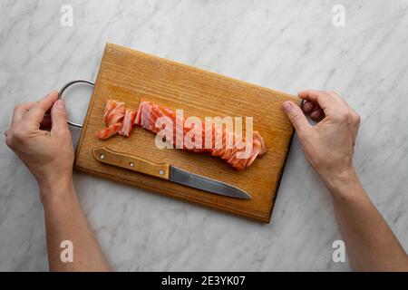 donna tritato salmone salato su tavola da cucina Foto Stock