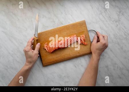 donna tritato salmone salato su tavola da cucina Foto Stock