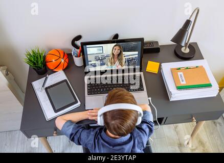 Vista dall'alto di un ragazzo irriconoscibile con cuffie che ricevono la classe a. casa con computer portatile Foto Stock