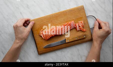 donna tritato salmone salato su tavola da cucina Foto Stock