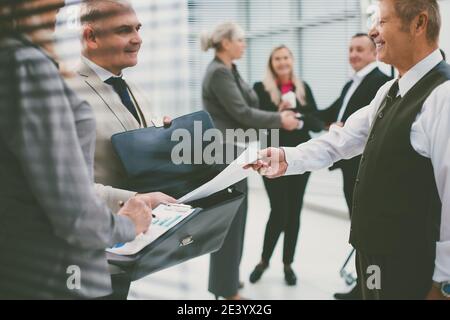 primo piano. uomo d'affari riuscito che consegna il documento al suo socio di affari. Foto Stock