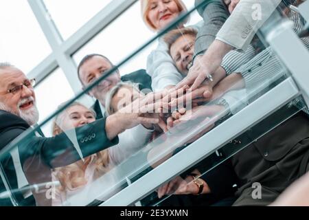 Gruppo di dipendenti che si uniscono ai loro palmi sopra la scrivania. Foto Stock