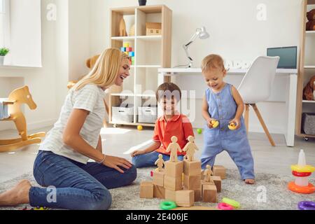 Felice madre di famiglia e due bambini che costruiscono piramide di legno dettagli insieme a casa Foto Stock