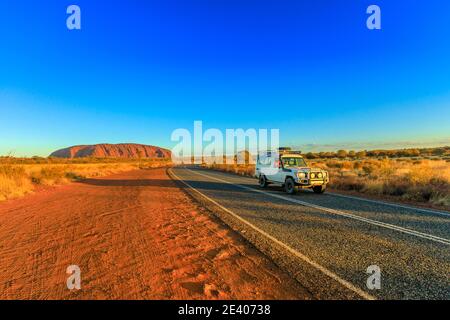 Uluru, Territorio del Nord, l'Australia - Agosto 25, 2019: 4X4 veicolo sulla strada che conduce al maestoso monolito di Uluru Ayers Rock in Uluru-Kata Tjuta Foto Stock