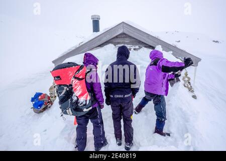 Sciatori in una spedizione di sci alpinismo scavando una neve Capanna legata nelle montagne della Norvegia Foto Stock