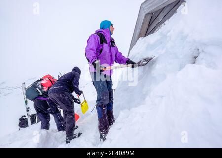 Sciatori in una spedizione di sci alpinismo scavando una neve Capanna legata nelle montagne della Norvegia Foto Stock