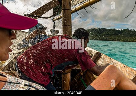 Navigazione in stile polinesiano su una barca a vela Proa (multiscafo a vela) nelle Isole Deboyne, Papua Nuova Guinea. Lo scafo è realizzato in legno duro sottile. È stretta, lunga e offre poco spazio. Durante il viaggio, l'acqua che si spruzzi viene continuamente convogliata verso l'esterno Foto Stock