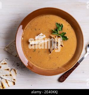 Ciotola di zuppa di fagioli servita con pane pita su sfondo di legno bianco, pasto vegano sano, cibo a base di piante Foto Stock