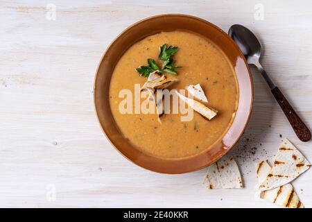 Ciotola di zuppa di fagioli servita con pane pita su sfondo di legno bianco, pasto vegano sano, cibo a base di piante Foto Stock