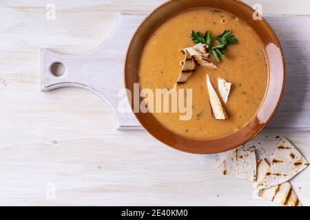 Ciotola di zuppa di fagioli servita con pane pita su sfondo di legno bianco, pasto vegano sano, cibo a base di piante Foto Stock