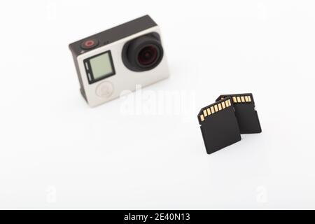 Due schede di memoria SD nere e Action Camera sfocata accesa Uno sfondo bianco Foto Stock